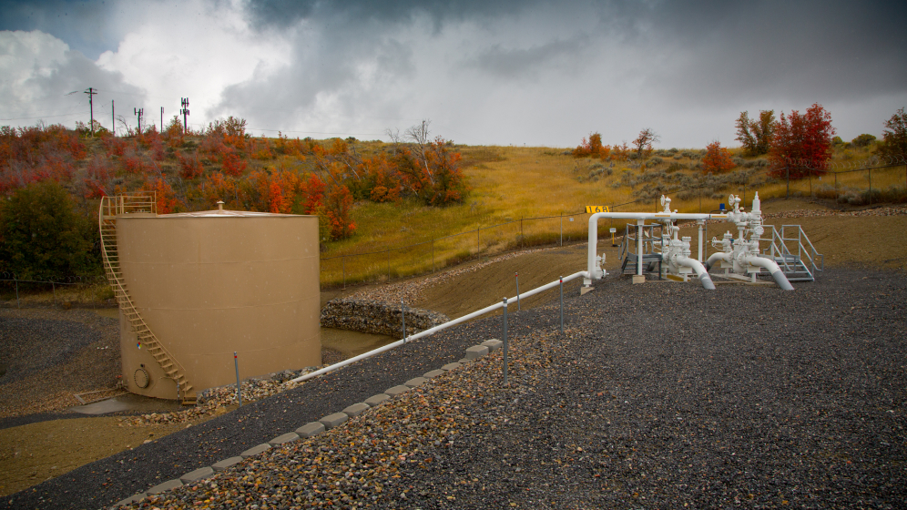 A small pipeline substation peaks out of the ground against the backdrop of the Colorado mountains. 